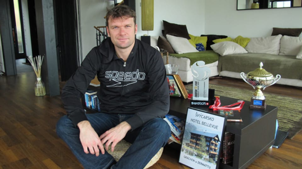 Martin Laciga in seinem Wohnzimmer in Kerzers - mit Pokalen und dem Bild des Familienhotels in Grächen.