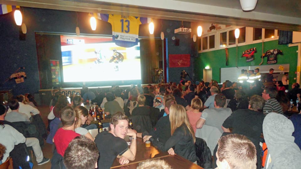 Gottéron-Fans schauen sich das Spiel in Düdingen auf Grossleinwand an.