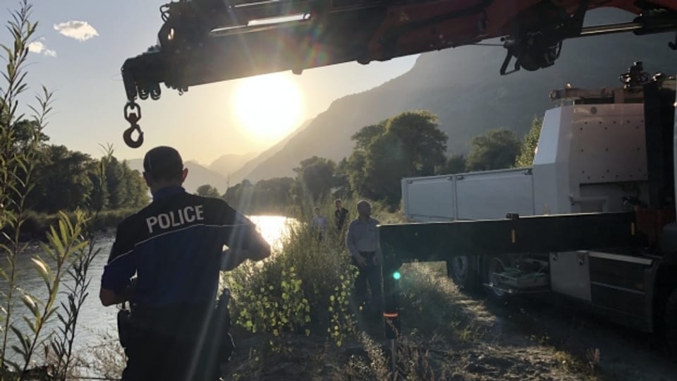 Polizisten der Kantonspolizei Wallis bergen ein Autowrack aus der Rhone bei Leytron.