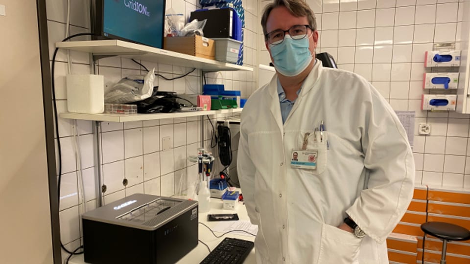 Adrian Egli in seinem Labor mit dem Gerät, das die beiden ersten Omikron-Fälle der Schweiz sequenzierte