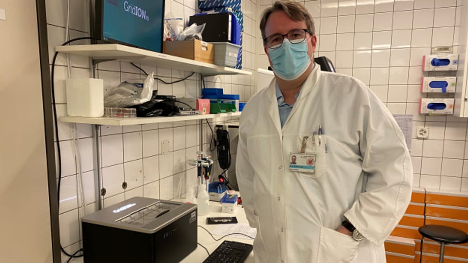 Adrian Egli in seinem Labor mit dem Gerät, das die beiden ersten Omikron-Fälle der Schweiz sequenzierte