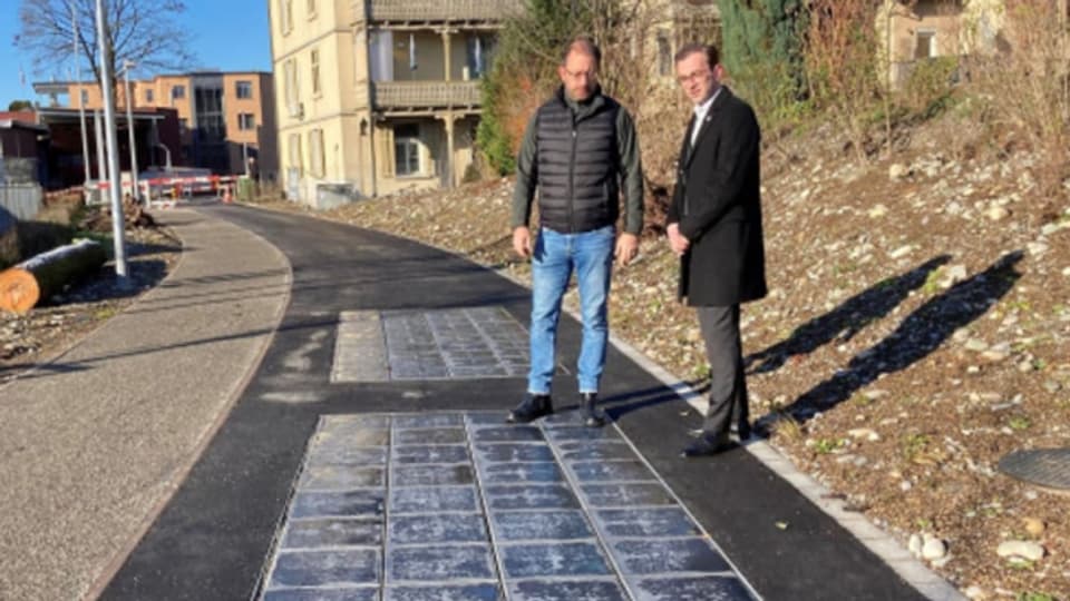 Gemeinderat Drin Alaj (rechts) und Projektleiter Antonio Milone bei den in die Fahrbahn des Papierigleiswegs eingelassenen Solarpflastersteinen aus rezykliertem Kunststoff