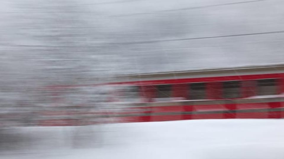 Eine Bahn fährt im Schnee am Fotografen vorbei
