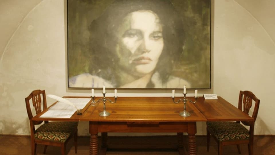 Ein Richtertisch und ein Porträt von Anna Göldi im ehemaligen Anna Göldi Museum in Mollis.