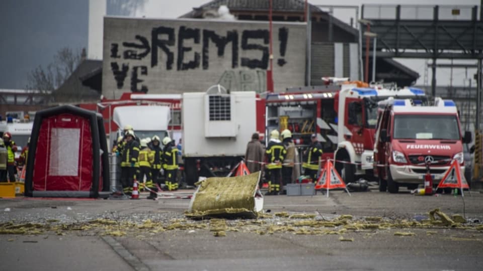 Trümmer liegen auf der Strasse vor Fahrzeugen der Feuerwehr nach einer Explosion bei der Chemiefirma Rohner in Pratteln.