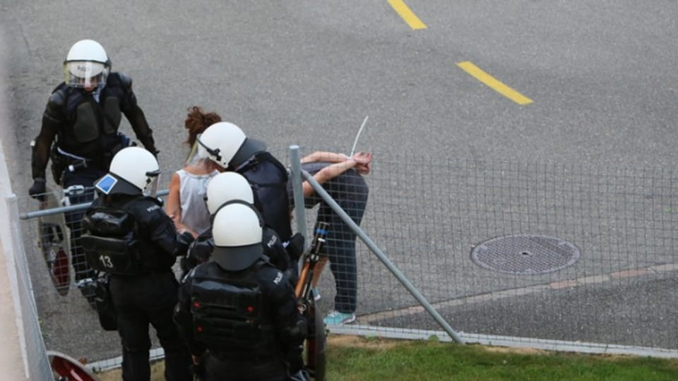 Polizisten kontrollieren eine Aktivistin beim Binz-Areal.