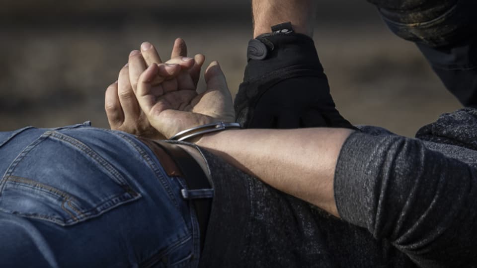 Ein Polizist legt einem Mann Handschellen an