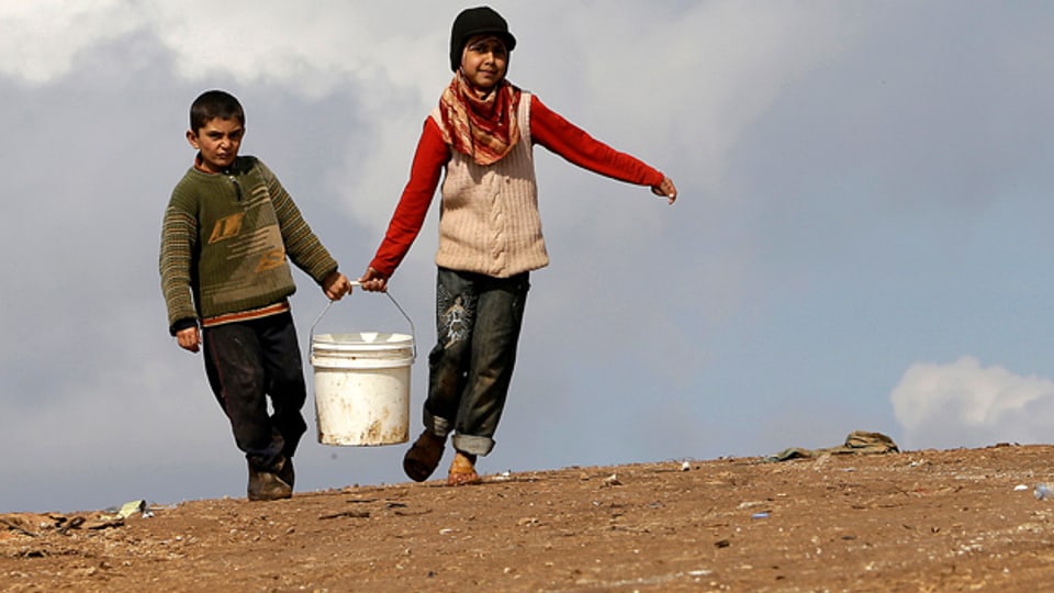 Flüchtlingskinder tragen einen Wassereimer im Atmeh Flüchtlingslager im Norden Syriens.