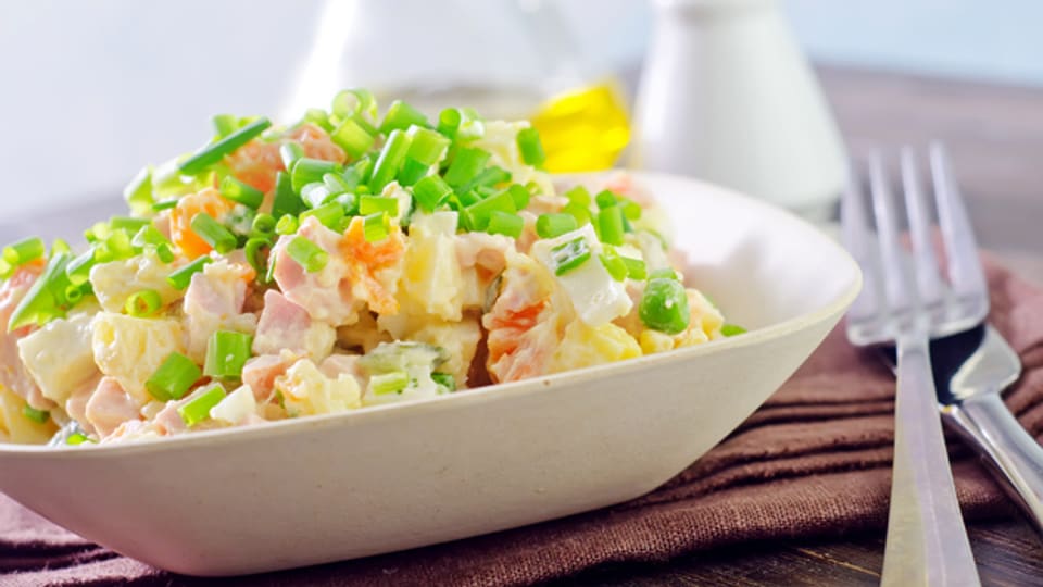 Russischer Salat besteht heute aus gekochten Kartoffeln, Karotten, Erbsen, Salzgurken, Pouletfleisch und Eiern.