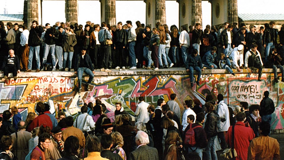 Der Tag nach der Öffnung: Menschen steigen am 9. November 1989 auf die Berliner Mauer vor dem Brandenburger Tor.