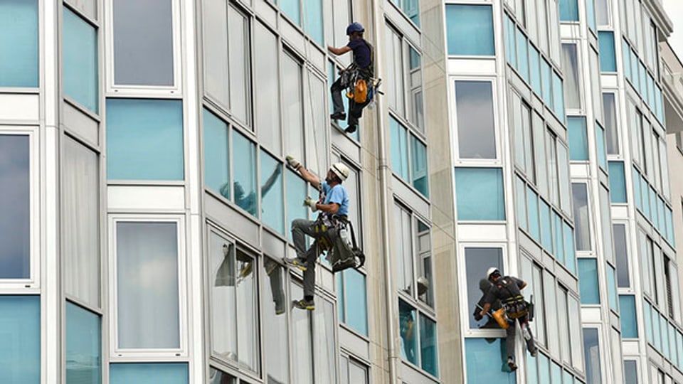 Alpinisten reinigen eine Glasfassade in Genf.