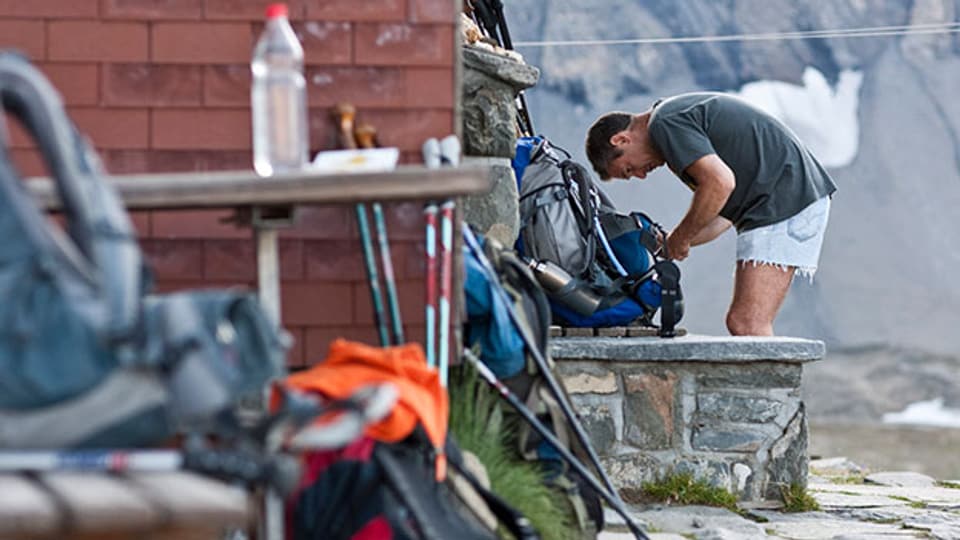 Ein Wanderer packt vor der Muttseehütte bei Linthal im Kanton Glarus seinen Rucksack.