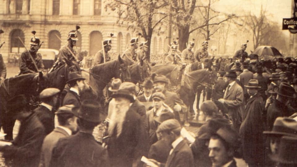 Das Bild zeigt den Paradeplatz 1918. Zu sehen sind Militär-Kavallerie Soldaten, die Streikende einkesseln.