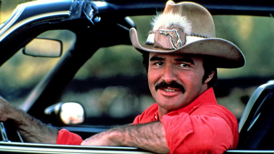 Burt Reynolds in “Smokey and The Bandit” in einer rasanten Autojagd und viel Countrymusik.