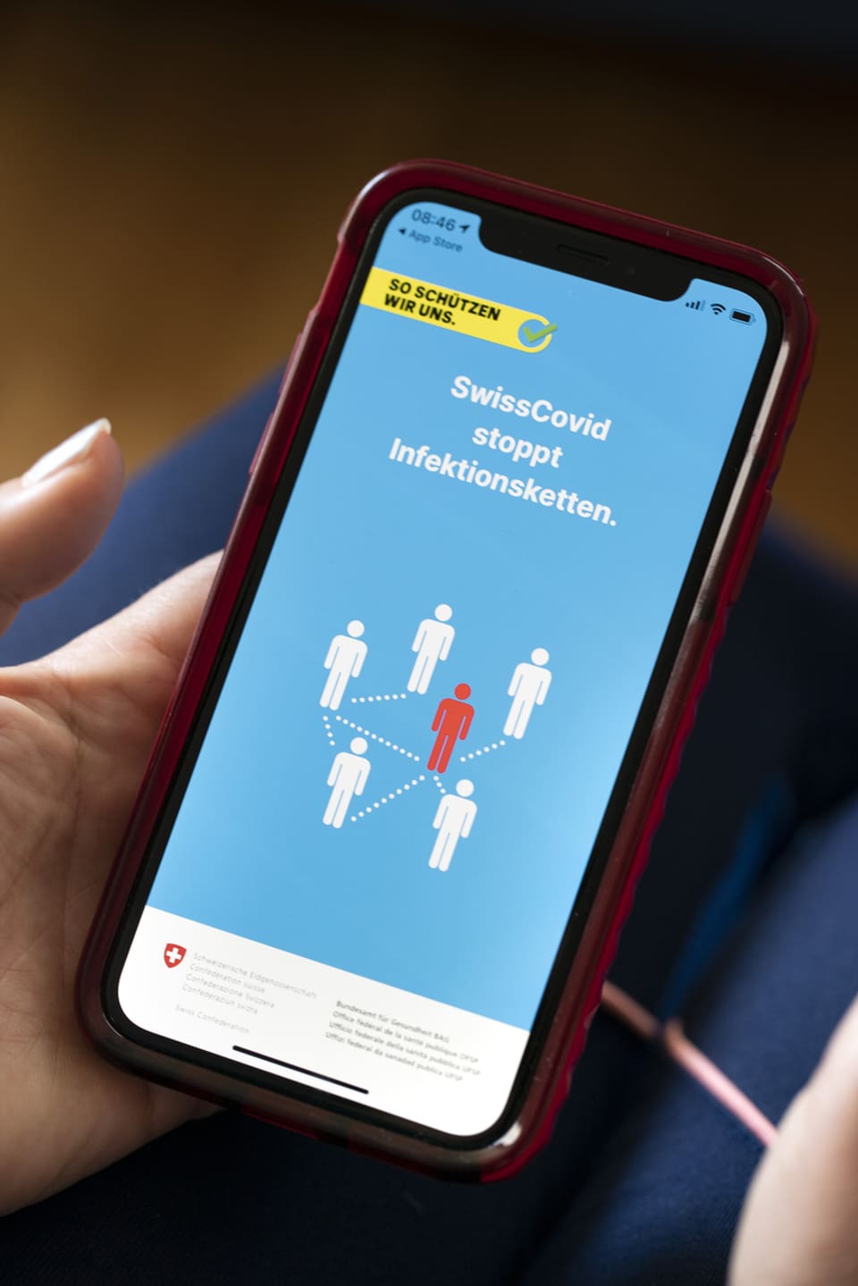 Eine Frau installiert die SwissCovid Contact Tracing App auf ihrem Smartphone.