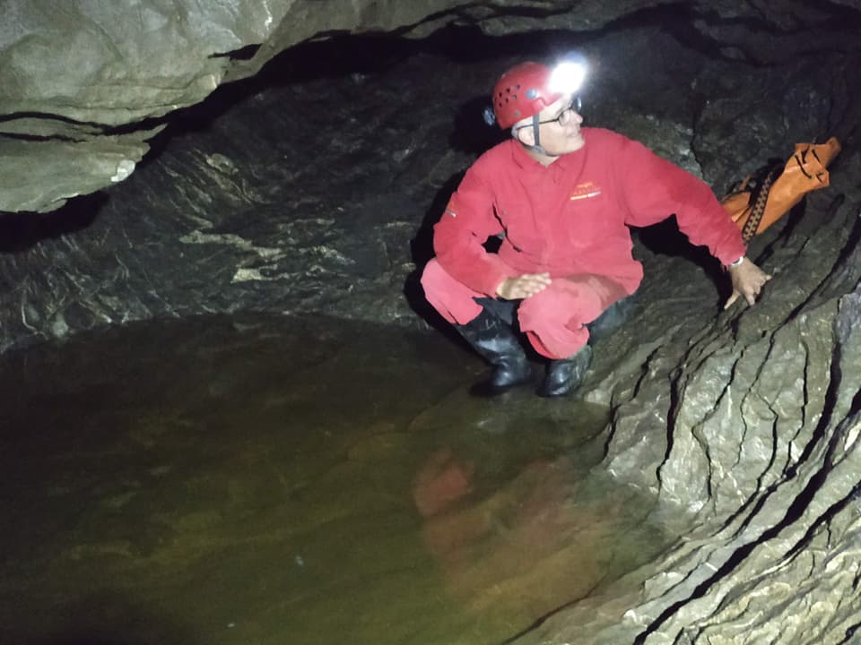 Marcel Hähni mit Overall, Helm und Stirnlampe in der Höhle.