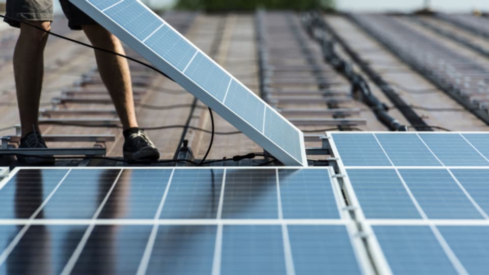 Auf einem Dach werden Solarpanels installiert