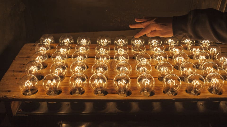 Ein Mitarbeiter einer Firma testet Glühbirnen.