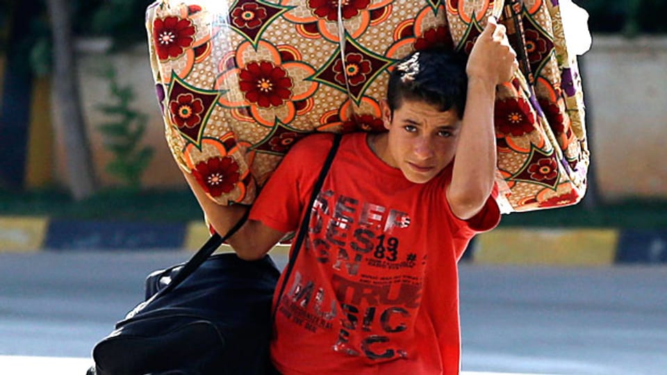 Alles, was er tragen kann: Ein Junge aus Syrien flüchtet mit seiner Familie über die türkische Grenze aus seiner Heimat.