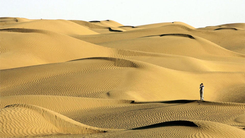 Eine Besucherin in der Taklimakan Wüste in China.