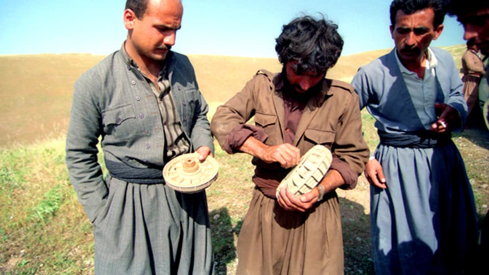 Drei Männer entschärfen eine Landmine.
