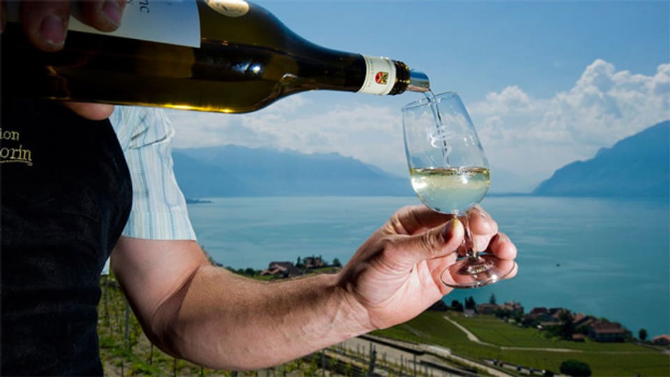 Ein Winzer serviert seinen Wein in Chexbres, hinter ihm der Genfersee.
