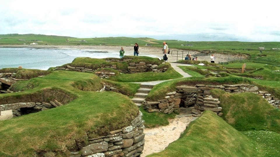 Besucher erkunden das Dorf Skara Brae auf den schottischen Orkney Inseln.