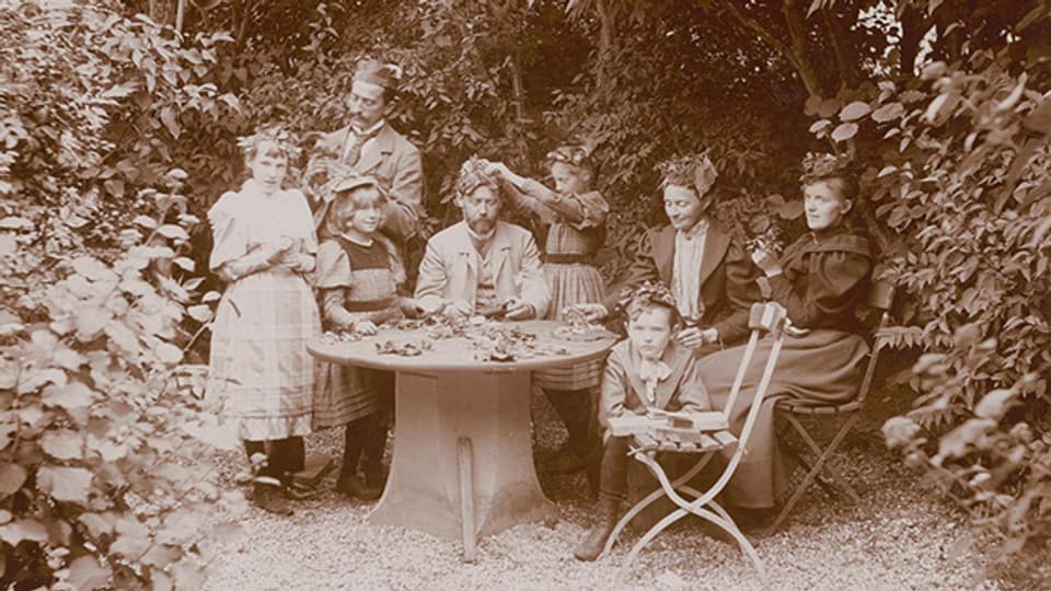 Familie im Garten. Was die Kopfbedeckungen bedeuten, ist leider unbekannt (1886).