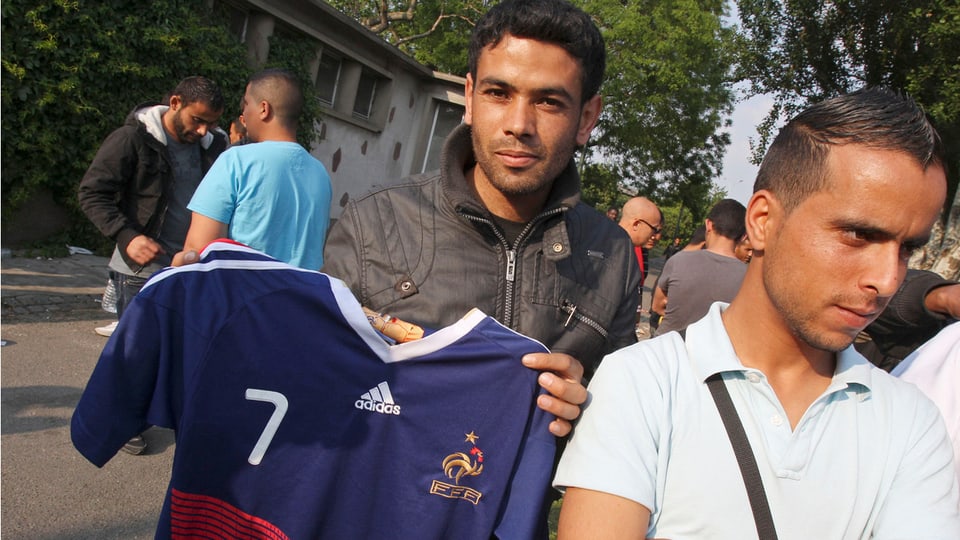 Ein Tunesier hält ein französisches Fussballdress.