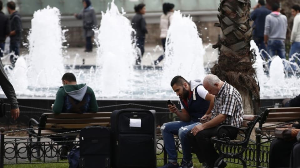 Syrische Flüchtlinge in Istanbul auf Parkbänken sitzend