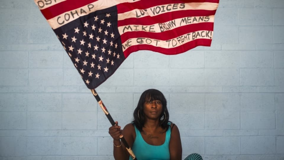 Eine schwarze Aktivistin schreibt deutliche Botschaften auf die US-Flagge.