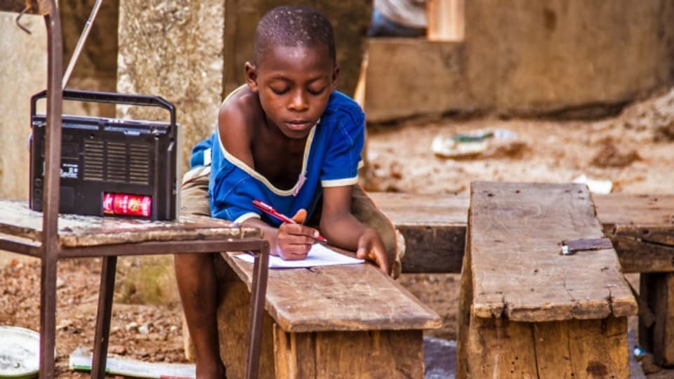 Ein Junge in Sierra Leone verfolgt den Schulunterricht aus dem Radio