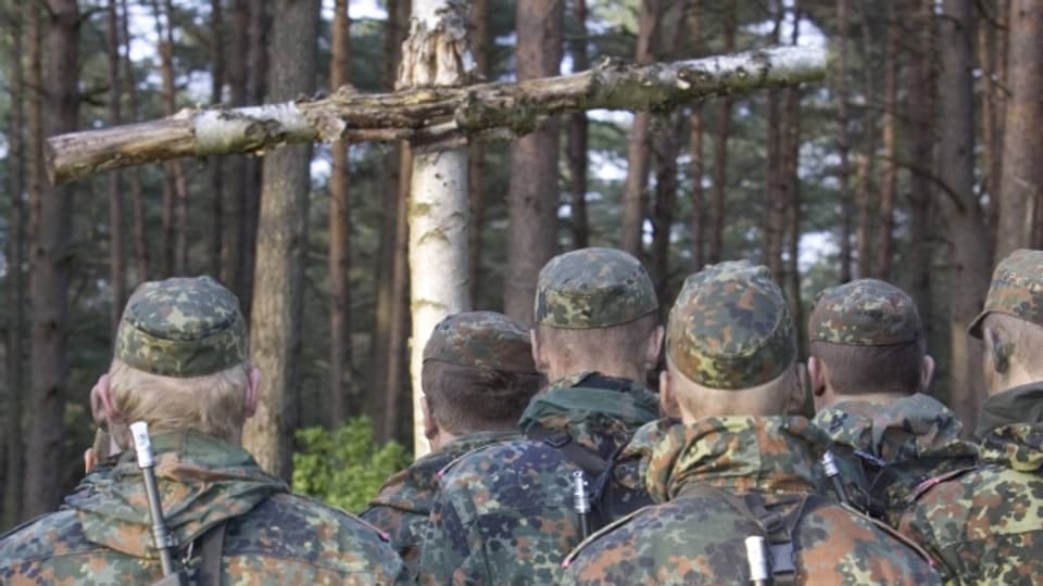 Rekruten der deutschen Bundeswehr vor einem Kruzifix aus Holz
