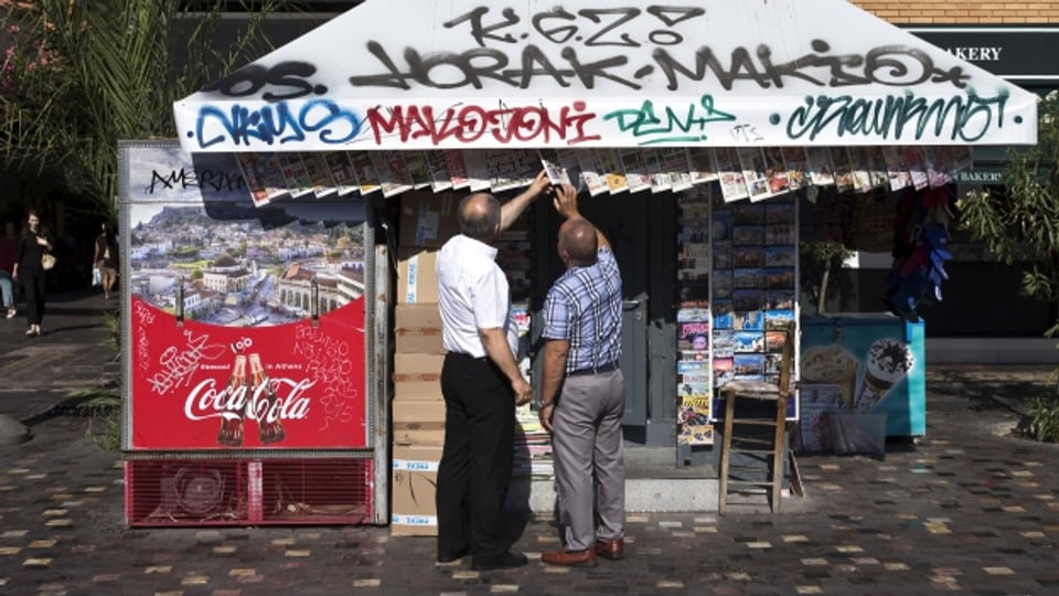 Zwei Männer vor einem Zeitungsstand in Griechenland.