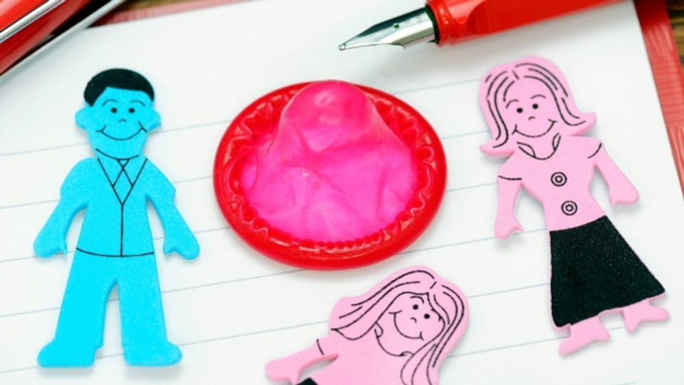 Ein Kondom, ein Stift und Figuren von Mann, Frau und Kind liegen auf einem Schreibblock