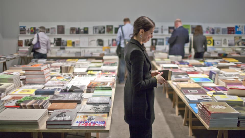 Besucherin der Art Basel schmökert in Kunstbüchern.