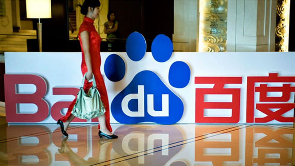 Eine Chinesin spaziert am Firmenlogo von Baidu vorbei.
