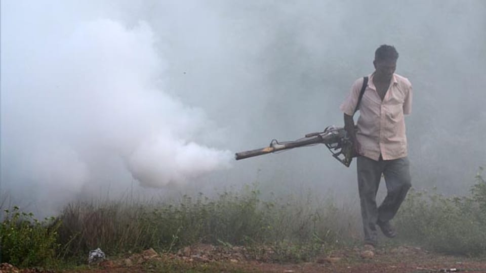 Ein indischer Arbeiter räuchert ein Gebiet im Kampf gegen Malaria aus.