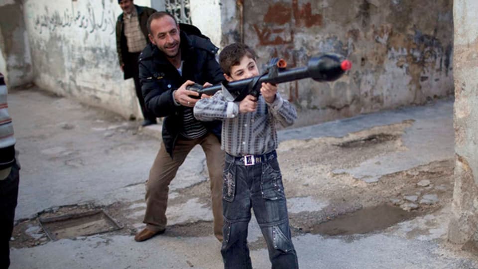 Ein Mann im syrischen Idlib erklärt dem 11-Jährigen Bilal, wie man eine Spielzeug-Panzerabwehrrakete bedient.