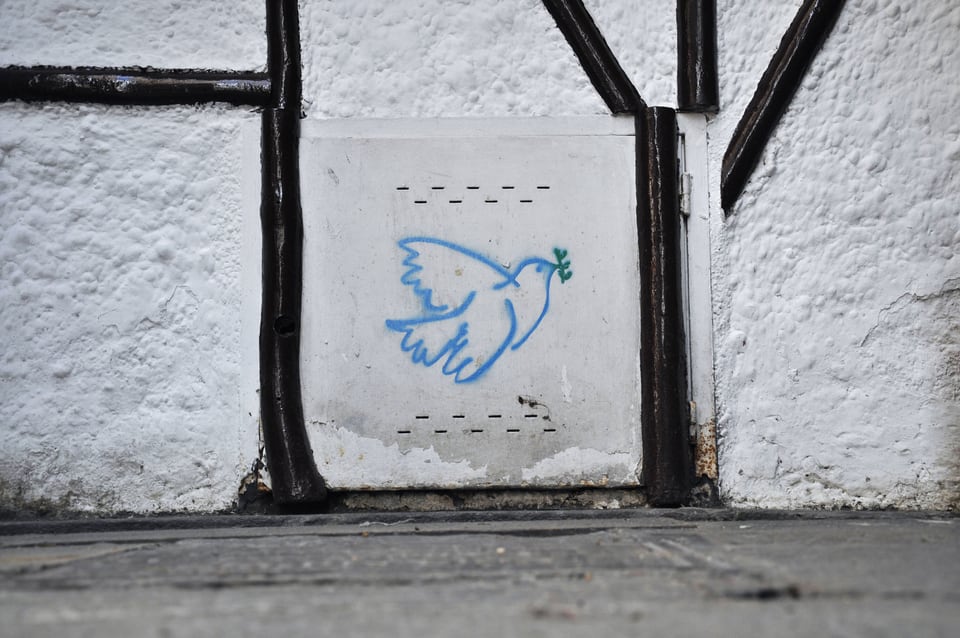 Graffiti einer Friedenstaube an einer Häuserwand in Barcelona.