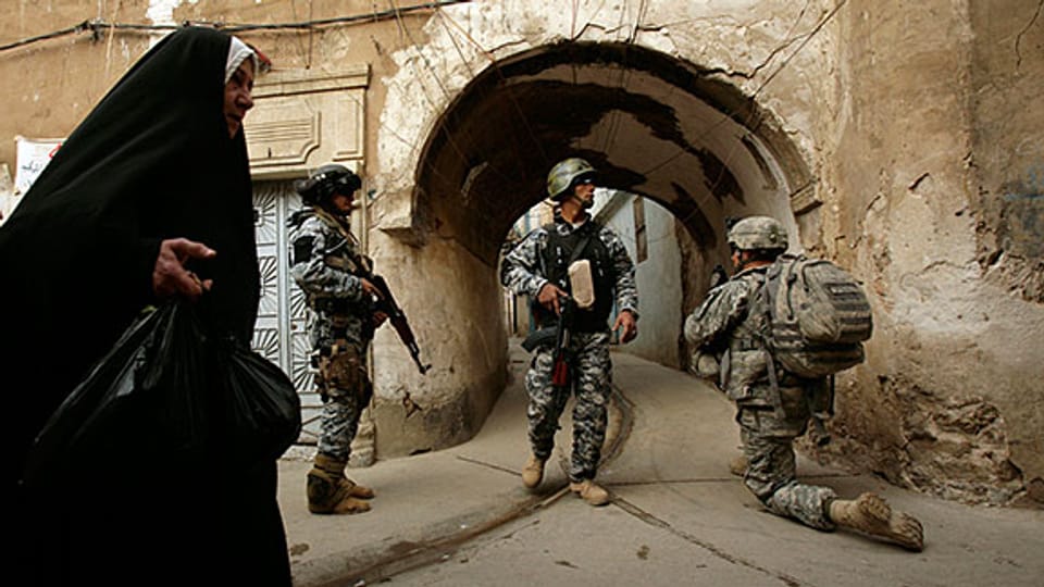 2009: Eine irakische Frau geht an US-Soldaten vorbei.