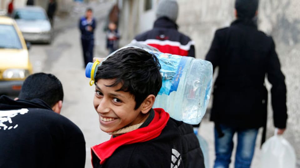 Ein Junge trägt eine Wasserflasche nahe Damaskus