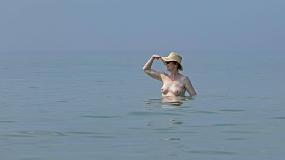 Frau oben ohne mit Hut im Wasser