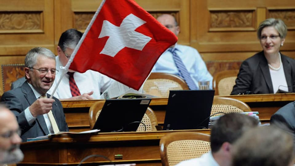 Walter Müller (FDP/SG), links, schwenkt eine Schweizerfahne waehrend den Beratungen über das Amtshilfegesuch der USA.