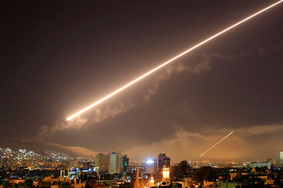 Der Nachthimmel über Damaskus wird von einer Rakete erhellt.