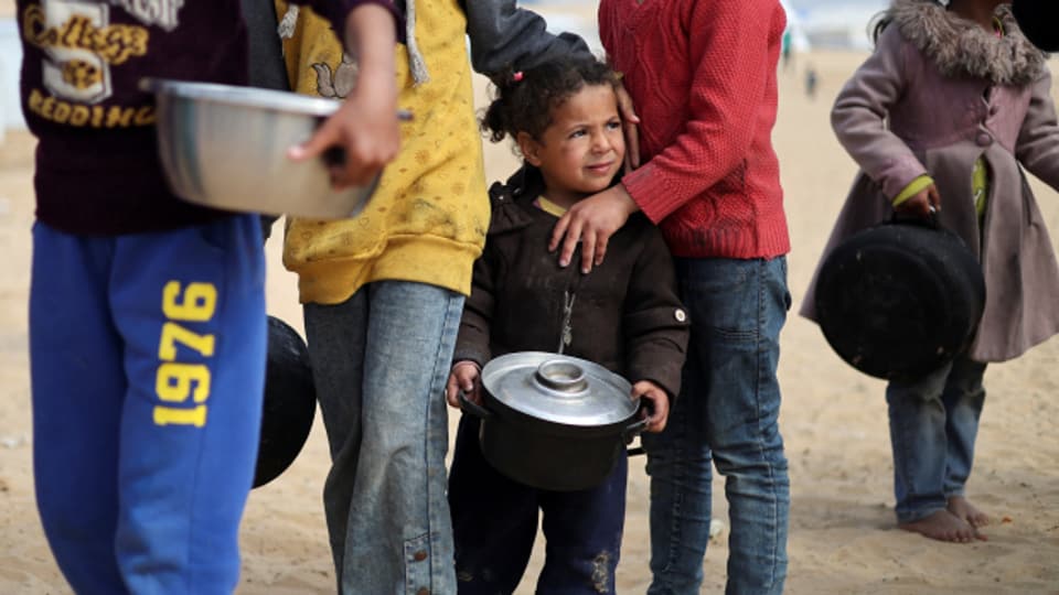 Vertriebene palästinensische Kinder warten in einem Zeltlager in Rafah auf die Ausgabe von Essen.