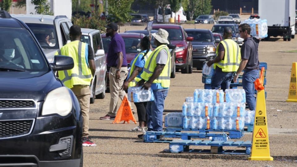 Helfer verteilen Trinkwasserflaschen an eine lange Schlange von Jacksons Einwohnern.