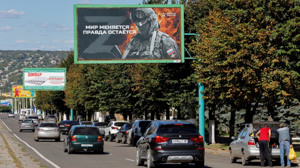 In Luhansk fahren Autos an Werbetafeln mit prorussischen Slogans vorbei.