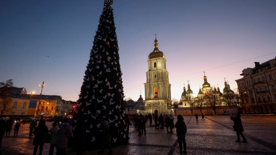 Menschen versammeln sich um einen unbeleuchteten Weihnachtsbaum auf dem Sofiyska-Platz in Kiew.