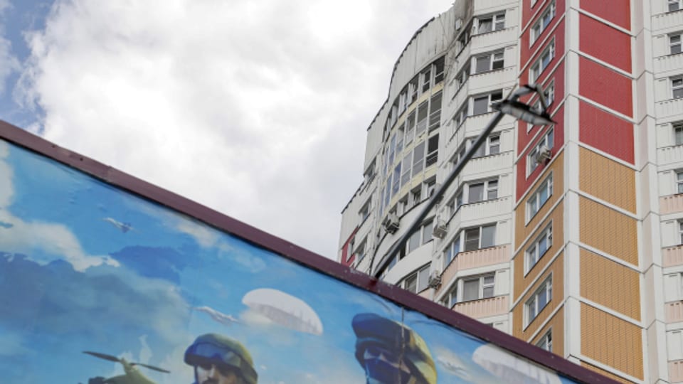 Ein Graffito mit Kriegspropaganda vor einem, durch den Drohnenangriff, beschädigten Gebäude im Moskau.